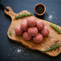 Boulettes d'agneau empilées sur planche en bois d'olivier, fond ardoise