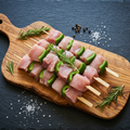 Brochettes de dinde sur planche en bois d'olivier, fond ardoise