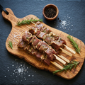 Brochettes d'agneau sur planche en bois d'olivier, fond ardoise