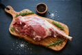 Gigot d'agneau frais sur planche en bois